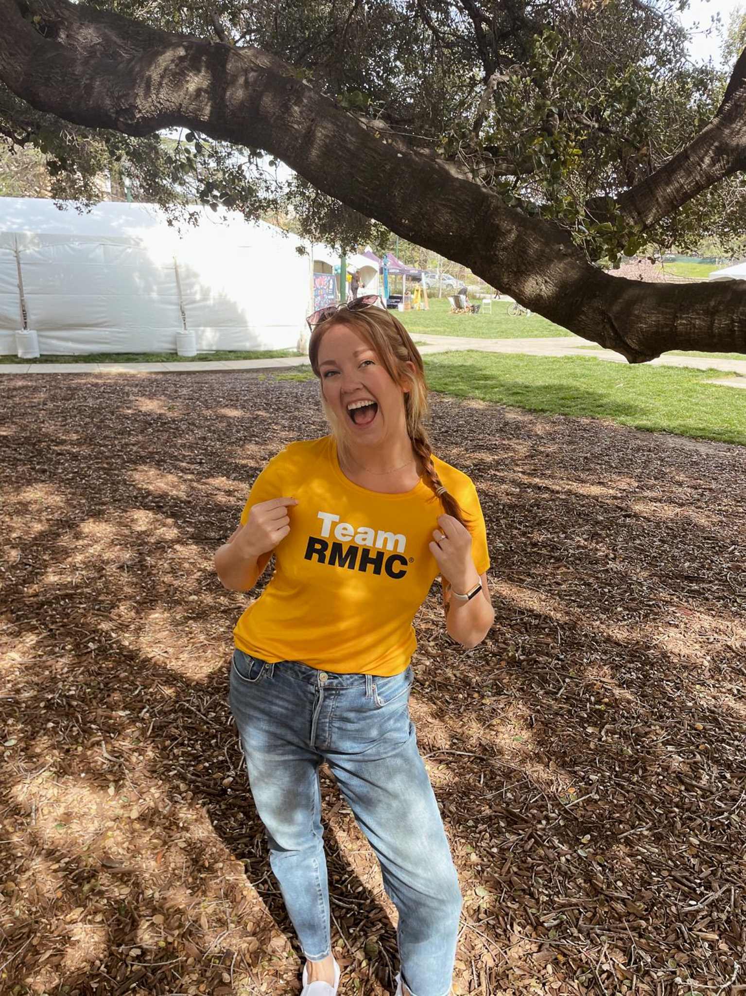 A excited person pointing at their yellow Team RMHC t-shirt.