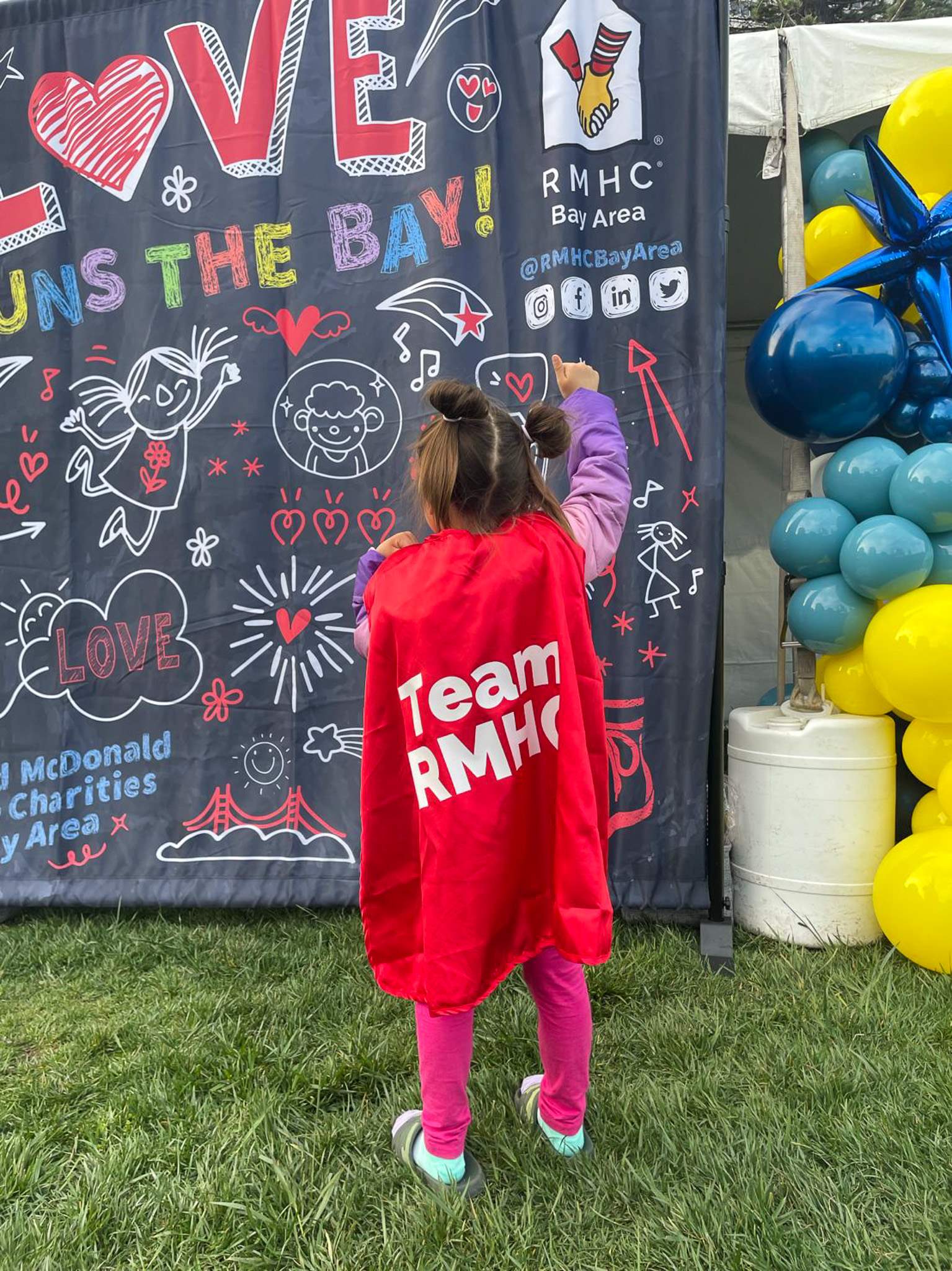 A child with a cape that has Team RMHC