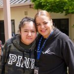 The Rosas Family: Two women smiling with arms around each other outside an RMHC facility, both wearing sweatshirts and lanyards.