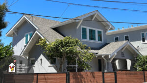 New! RMH Oakland. Two-story gray building with white trim and a wooden fence, home to Ronald McDonald House Oakland.