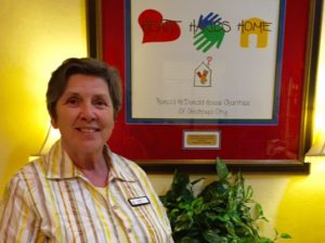 Smiling woman standing in front of a framed Heart Hands Home artwork at Ronald McDonald House Charities of Oklahoma City.