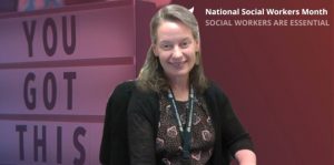 Smiling woman sits in front of a background that reads National Social Workers Month: Social Workers Are Essential, with a motivational sign that says You Got This.