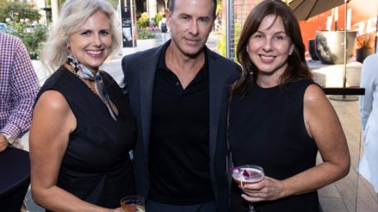 two woman and man pose with drinks