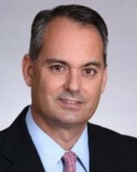 Headshot of board member Willie Hernandez, wearing a suit and smiling