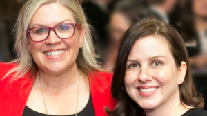 President Amy Oliver and CEO Laura Boudreau smiling at a formal event, with a blurred crowd in the background.