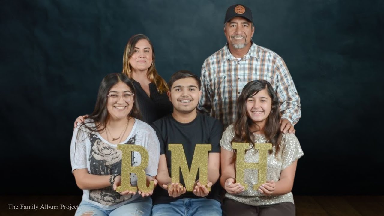 The Medina Flores family poses for a portrait holding gold glitter letters spelling RMH, as part of The Family Album Project.
